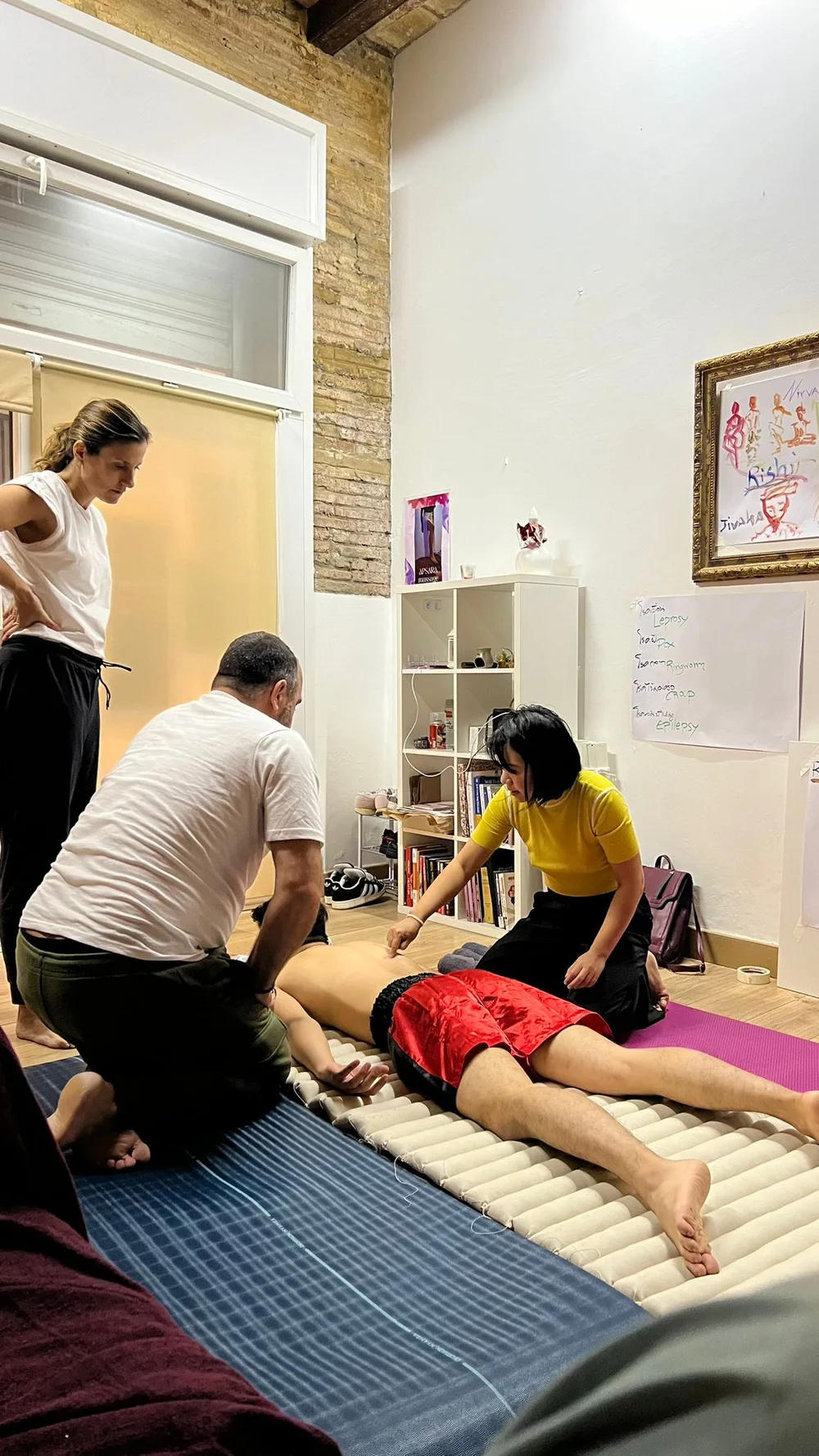 Two instructors correcting a student's hand position during floor practice