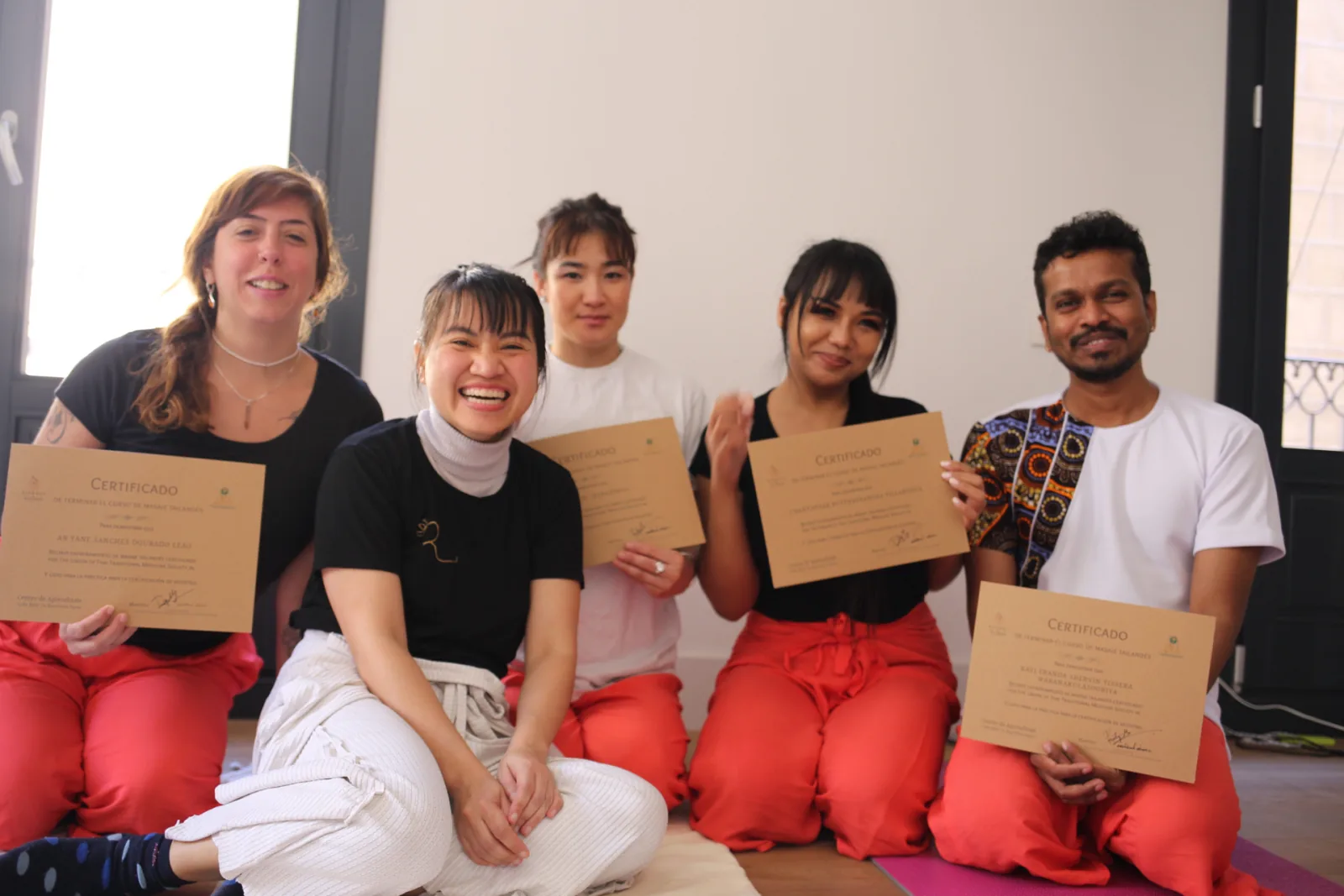 Five students holding their certificates after completing a Thai massage course in Barcelona